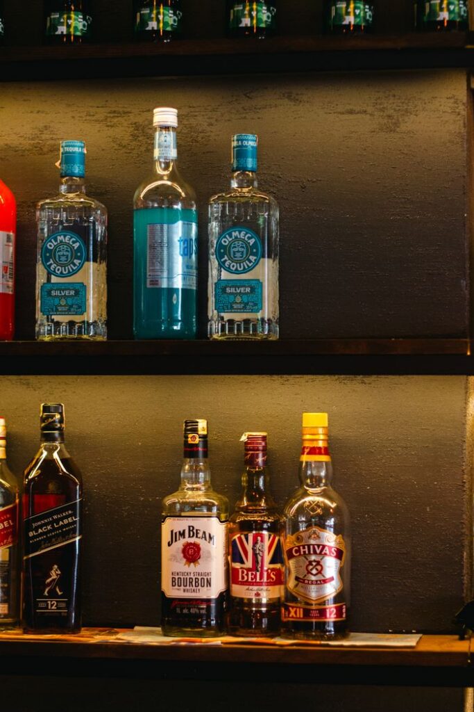 Colorful liquor bottles neatly arranged on a bar shelf, showcasing various brands.