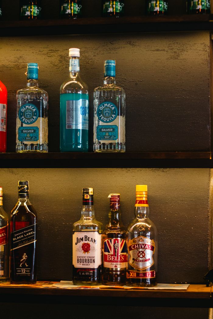 Colorful liquor bottles neatly arranged on a bar shelf, showcasing various brands.